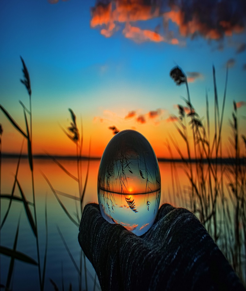 A creative crystal lens ball photography of a lake with greenery around at dawn
